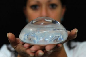 a woman holds BREAST IMPLANTS in her hands