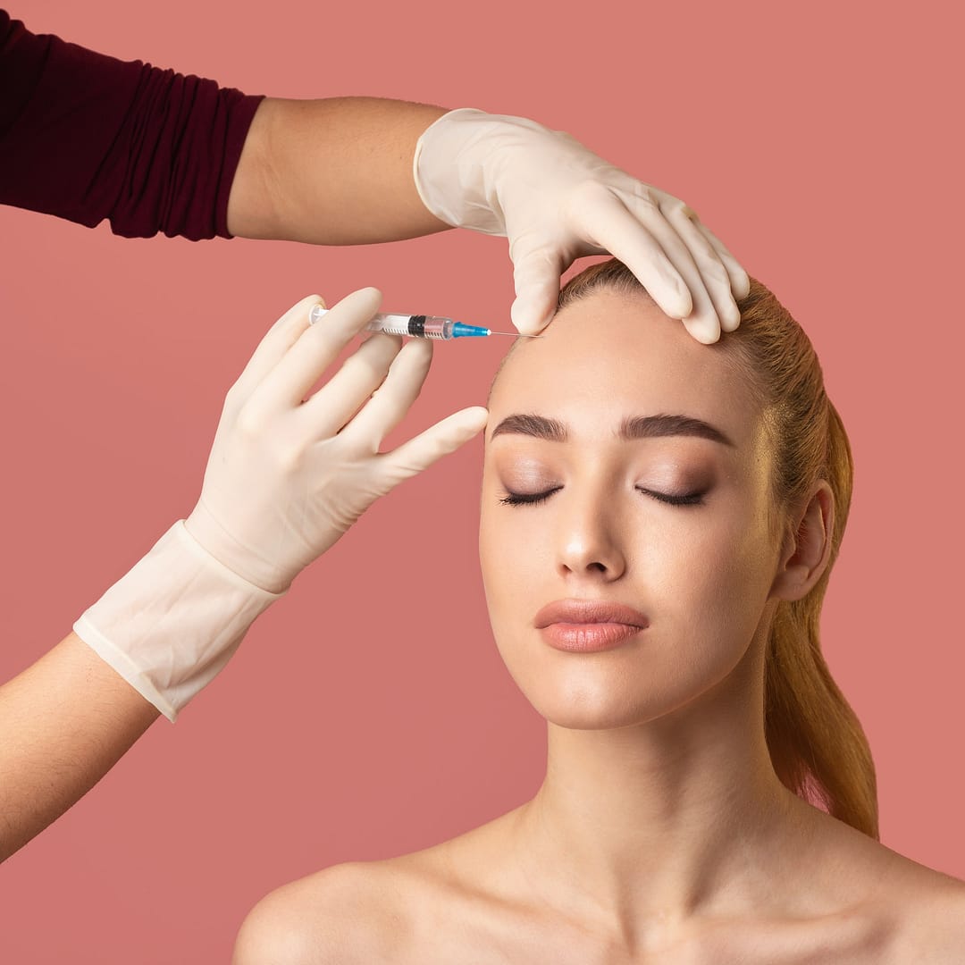 Woman Getting Beauty Injection In Forehead Smoothing Skin, Pink Background